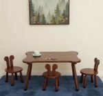 dark mahogany wooden kids activity table and chairs set, featuring a montessorie study table with rounded corners paired with three matching rabbit eared wooden chairs on a blue rug.