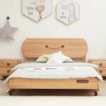 Direct front view of the smiley-face carved wooden bed frame centered between two matching double-drawer nightstands.