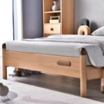 Close-up side perspective of a natural solid wood single bed frame featuring dark wood accent post tops, rounded child-safe corners, and side handles.