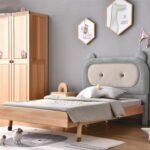 Side perspective of Amyzel padded grey bear ears single bed frame with light grey bedding and wooden wardrobe in background