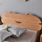 Close-up detail of solid wood carved bear ear headboard with subtle smile cut-out accent on wooden single bed