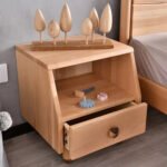Close-up shot of the Amyzel children's wooden bedside table with its bottom drawer pulled open, revealing colorful toy cogs and small play tools inside.