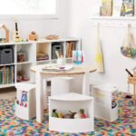 Amyzel multi-functional kids play table and chair set on a vibrant multi-color checkered nursery rug, minimalist white children's study furniture setup with bookshelves.