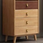 Scandinavian light oak 4-drawer chest featuring splayed wooden legs, brass hardware, and a dark walnut top accent drawer.