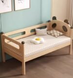 Cute panda-themed natural timber toddler bed featuring integrated side safety rails and panda ear details, styled against a mint green accent wall in a kids bedroom.