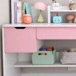 Detailed shot of pastel pink drawer fronts and lower open shelving featuring a sage green storage box and fabric organizational pouch.