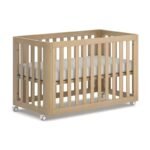 Natural light wood slatted baby crib equipped with lockable caster wheels and a comfortable white nursery mattress.