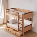 Light natural wood bunk bed styled in a cozy children's bedroom, featuring a built-in back wall bookshelf, attached vertical ladder, and two under-bed storage drawers.