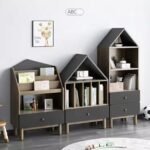 complementary house-shaped grey wooden bookshelf models (A, B, and C) arranged side-by-side in a modern child's playroom setting.
