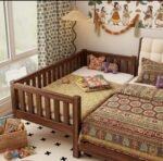walnut finish solid wood side-sleeper toddler bed attached to a parent bed