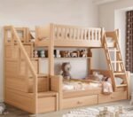 Multi-functional light pine wood twin bunk bed with two access points: left-side storage stairs and a right-side slanted ladder, complete with a built-in toy shelf and lower storage drawers.