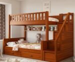 Warm honey finish wooden twin bunk bed featuring a right-side storage staircase with safety handrails, an inner full-length display shelf, and spacious dual under-bed pull-out storage drawers.