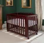 wooden infant crib with vertical slats and wheels in mahogany stain