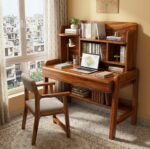 Honey finish solid wooden study table with rich grain patterns, built-in hutch bookshelf, bottom storage shelf, and matching cushioned chair near a window.