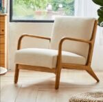 Minimalist off-white linen accent armchair with light oak wood frame styled near window over hardwood floor