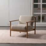 Three-quarter front view of oak wood frame lounge chair with off-white fabric upholstery in modern room setup