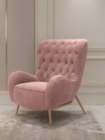 Mid-century modern dusty rose pink velvet wingback armchair featuring diamond button tufting and sleek gold legs in a luxury living room.