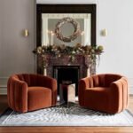 Pair of modern rust brown velvet channel-tufted swivel accent chairs arranged in a luxury living room around a fireplace decor setting