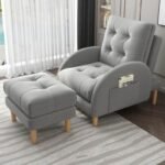 Soft grey plush recliner chair and footrest set accessorized with a cloud pillow in a cozy bedroom window reading nook.