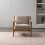 Modern mid-century accent armchair with cream textured fabric upholstery and natural oak wood frame front view