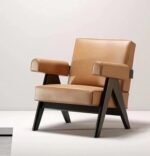 Camel tan leather mid-century modern armchair featuring thick padded armrests and dark wood V-frame legs on a light background