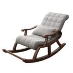 Dark wood rocking armchair upholstered in tufted light grey fabric with matching support pillow on white background.