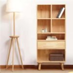 Full product view of the multi-tier bookcase featuring four top cubbies, a middle drawer, a lower open shelf, and tapered solid wood legs.