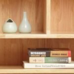 Detail shot of upper open shelves holding decorative ceramic vases and stacked books.