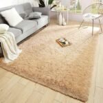 Amyzel warm beige fluffy shag area rug for contemporary living room, soft high pile tan plush carpet arranged under a grey contemporary sofa and minimalist wire chair.