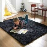 Amyzel dark charcoal grey fluffy shag rug for kids bedroom, thick plush dark grey playroom floor carpet with a boy reading a book next to a white play teepee.