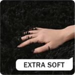 Hand sinking into premium extra soft black fuzzy rug, close up texture of thick high pile shag carpet for kids bedroom playroom floor.