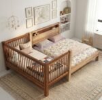 Bright and cozy modern bedroom showcasing a natural light wood bedside cot extension securely attached to a parents' double bed, styled with minimalist floral sheets and neutral nursery decor.